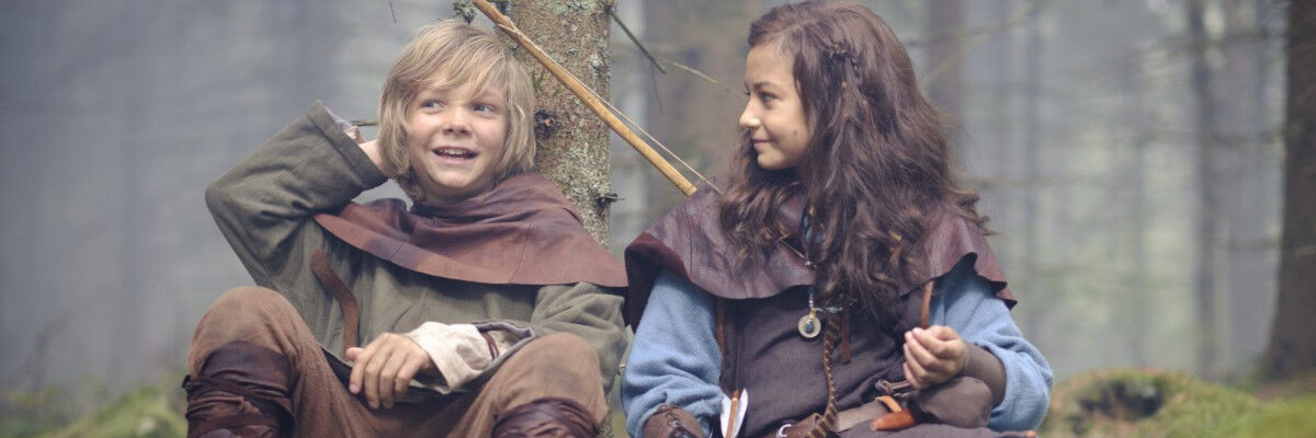 Kadr z filmu. Chłopiec i dziewczynka siedzący w lesie. 