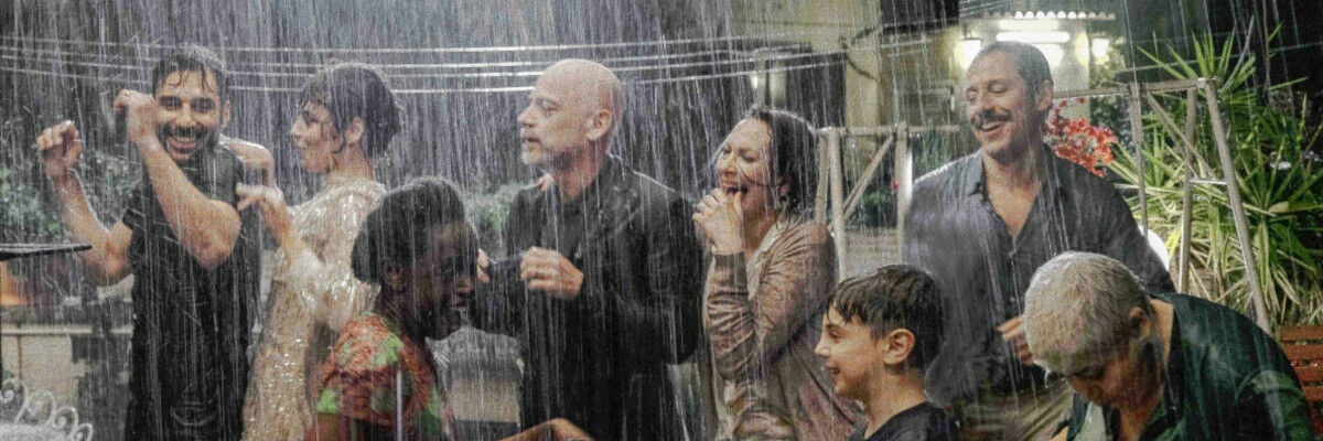 Kadr z filmu. Grupa tańcząca w deszczu ludzi. 
