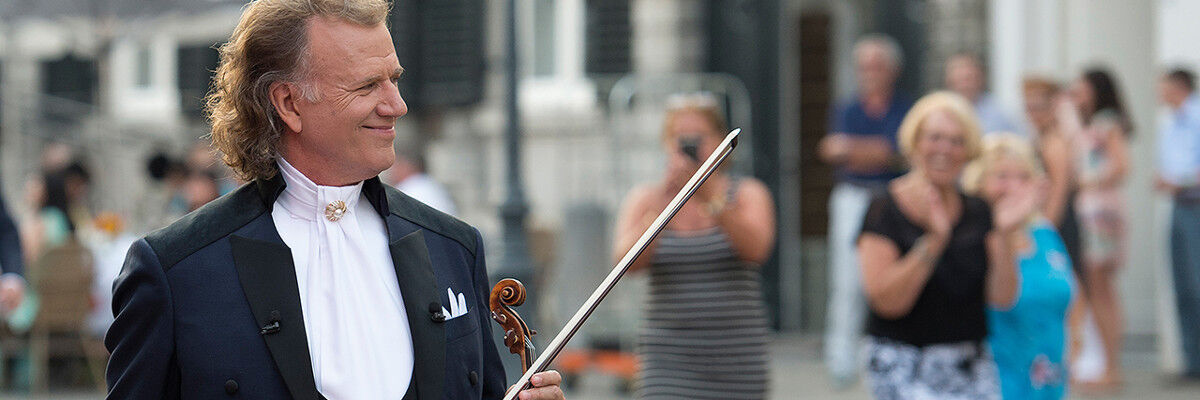 Andre Rieu idzie ulicą ze skrzypcami w ręku 