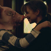 Kadr z filmu. Kobieta i chłopiec w masce świni przytulają się. 