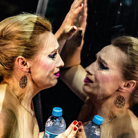 Zdjęcie ze spektaklu. Teresa Dzielska przeglądająca się w zwierciadle. Iwona Chołuj pukająca się w czoło.  