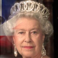 Elżbieta II stojąca na środku w koronie i sukni, po lewej stronie flaga Wielkiej Brytanii