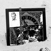 Młynek do kawy, dzbanek, kran, zegar z przyklejonymi zdjęciami rozrzucone na piasku