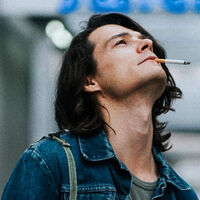 Młody mężczyzna z długimi włosami i papierosem w ustach