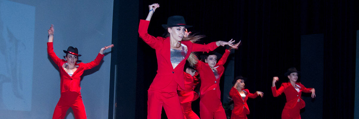 Tańczące dziewczyny na scenie w czerwonych strojach i czarnych kapeluszach