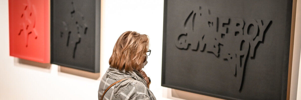 Kobieta oglądająca prace na wystawie „Przetrwają najsilniejsi”