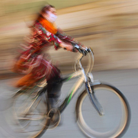 Uliczne fotografie Marcina Laskowskiego: dziewczynka w żółtej sukience, kobieta na rowerze, mężczyzna wiozący zgrzewki wody