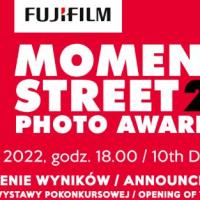 Na środku czarny napis Fujifilm na białym prostokącie, który jest na czerwonym tle, a niżej biały napis "Moment Street Photo Awards" i obok czarny napis "2022" na czerwonym tle