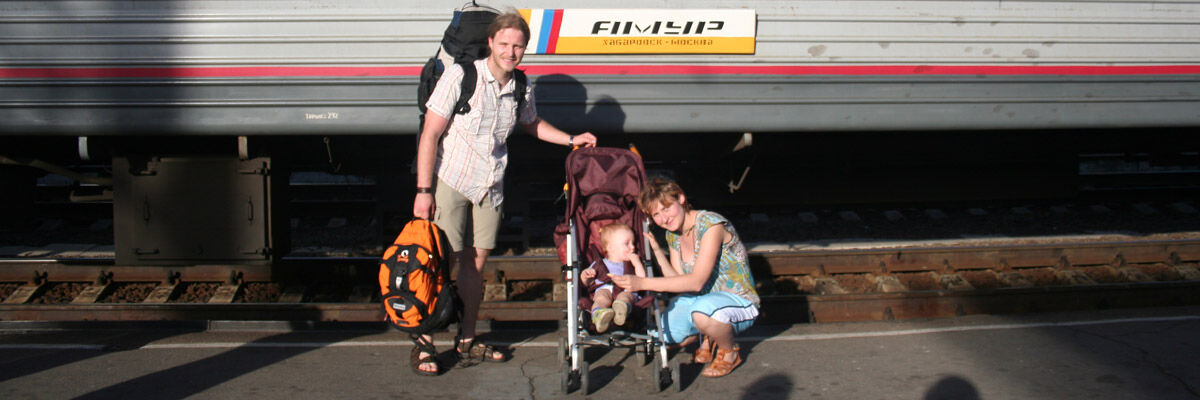 Podróżnik z plecakiem obok kobiety z dzieckiem w wózku na tle pociągu