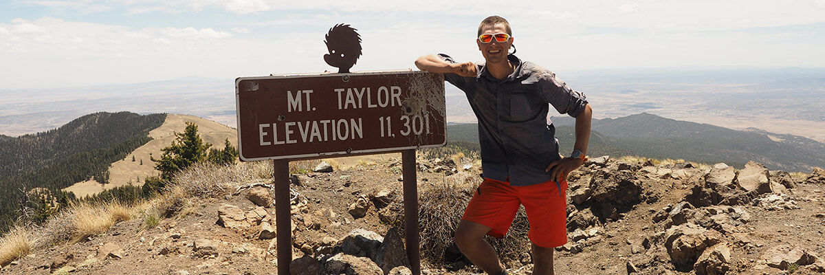 Podróżnik Grzegorz Ozimiński podczas górskiej wędrówki po USA obok znaku turystycznego