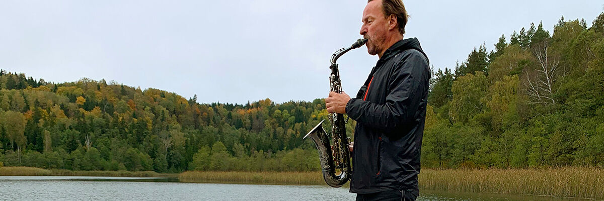 Mateusz Pospieszalski gra na saksofonie nad jeziorem 