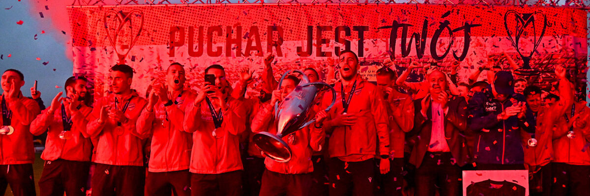 Zawodnicy Rakowa Częstochowy z Pucharem Polski, oświetleni mocnym czerwonym światłem, podczas fety